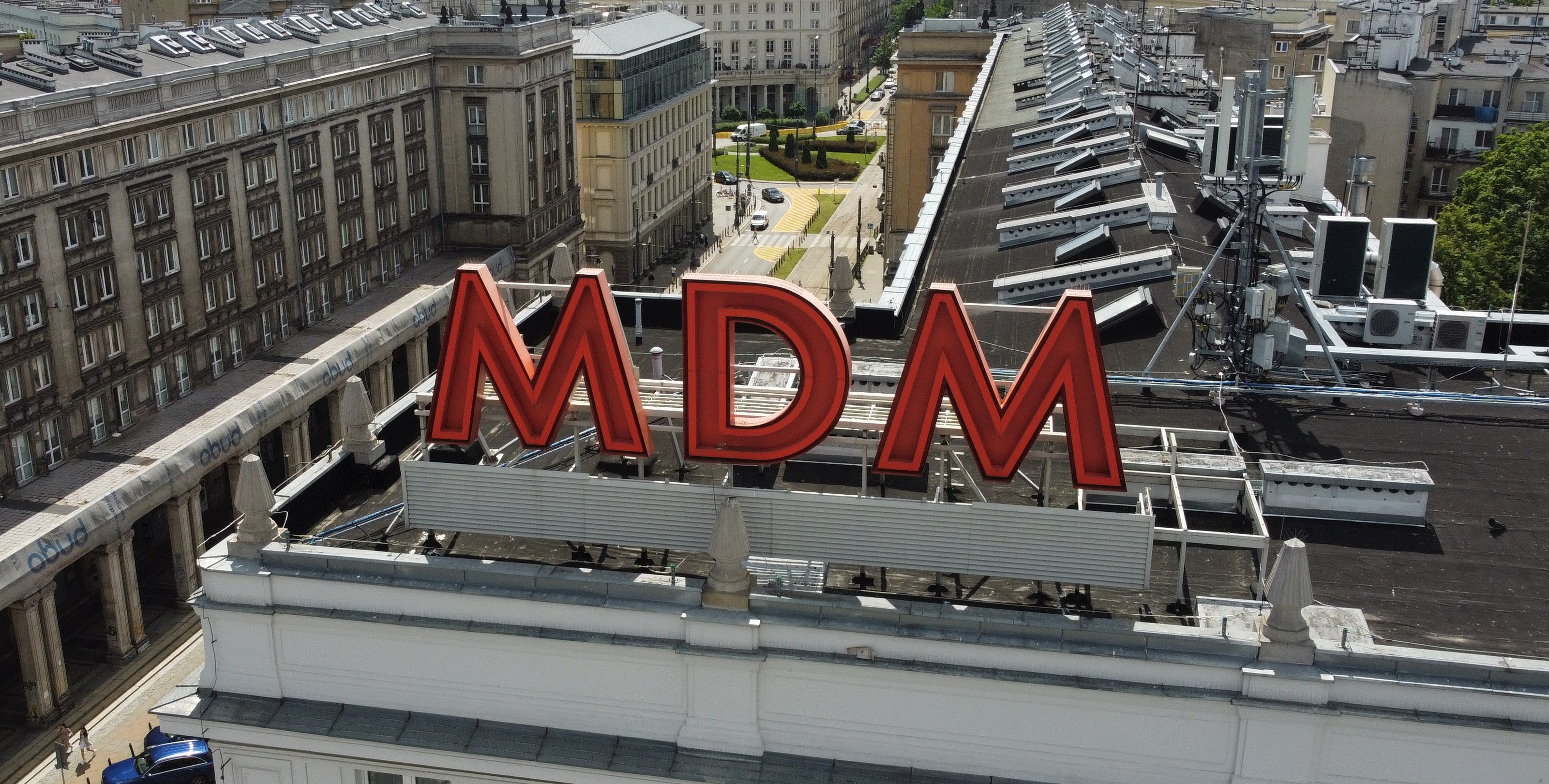 Nielegalna reklama chińskiej marki na dachu MDM-u. Przyćmiewa zabytkowy neon